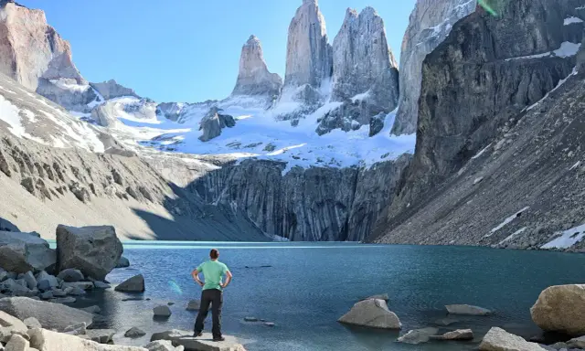 Widok na majestatyczne Torres del Paine w Chile. Turysta podziwia turkusowe jezioro i ośnieżone szczyty.