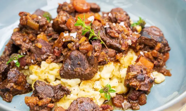 Herzhaftes Wildschwein Gulasch Rezept mit Spätzle, garniert mit frischen Kräutern und grobem Salz. Ein Genuss für Feinschmecker!