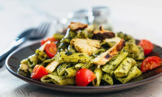 Penne z kurczakiem i pomidorkami, obficie polane aromatycznym makaronem z pesto bazyliowym. Pyszny obiad gotowy!