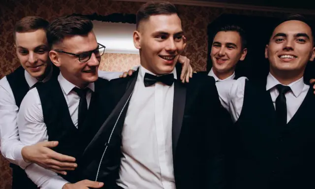 Uśmiechnięci panowie w garniturach, przygotowujący się na ekstremalny wieczór kawalerski.