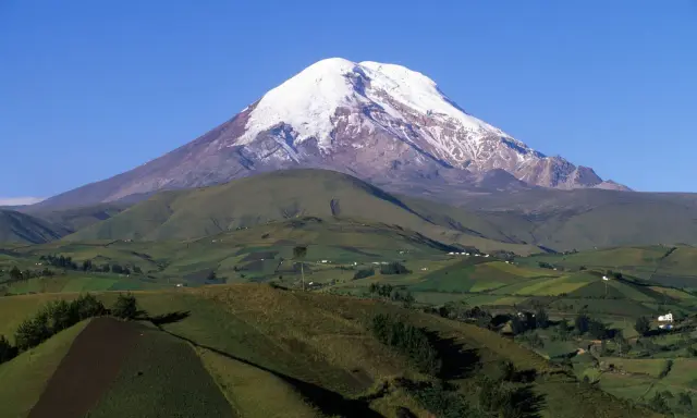 Ośnieżony wulkan Chimborazo, najwyższy szczyt Ekwadoru, góruje nad zielonymi wzgórzami, przypominając majestatem nawet Everest.