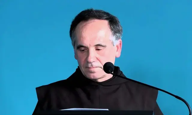 Mężczyzna w habicie przed mikrofonem, czytający psalm 140 tekst.