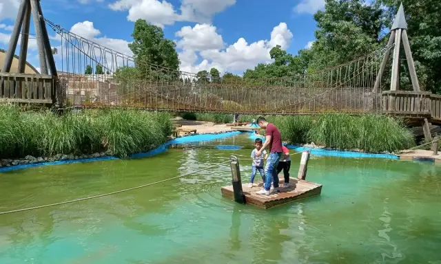 Un padre y sus hijos disfrutan de un día de aventura en un parque acuático en Valladolid con niños, navegando en una balsa.