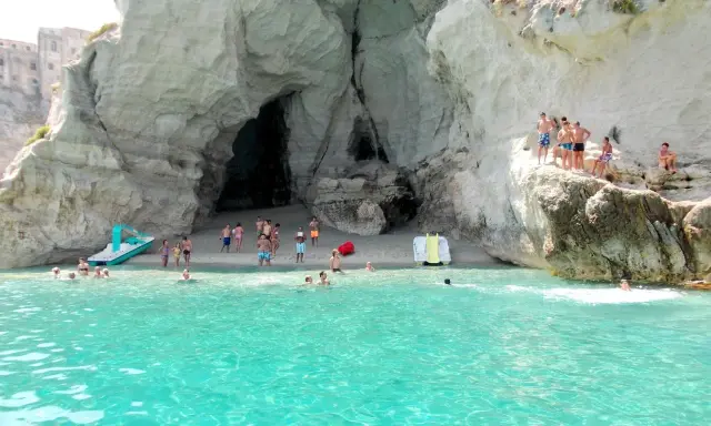 Bambini e adulti si divertono nella grotta del Palombaro, tra scogli e acque cristalline.