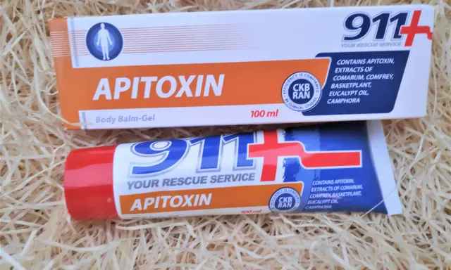 Dwa opakowania kremu z jadem pszczelim "Apitoxin" 911+ na tle słomy.