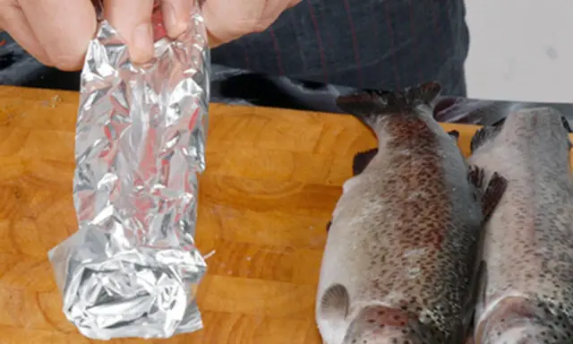 Vorbereitung für das Grillen: Ein Fisch wird in Alufolie gewickelt, bereit für den Weber Grill.