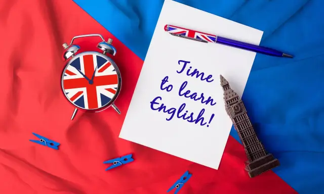 Budzik z flagą UK, długopis i napis "Time to learn English!" na tle brytyjskich barw. Czas na naukę!