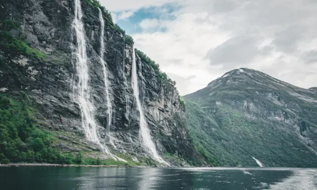 Siedem Sióstr, wodospad w Geirangerfjordzie, to jedno z najpiękniejszych miejsc w Norwegii. Woda spływa kaskadami po skalnej ścianie, tworząc spektakularny widok.