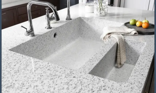 Évier de cuisine moderne en quartz ou granit, avec robinetterie chromée et une serviette pliée.