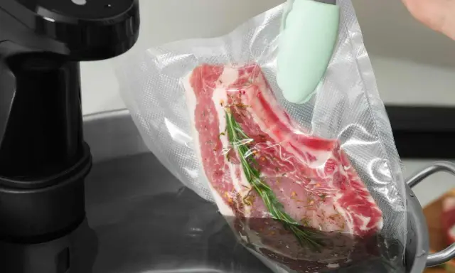 Ein Steak mit Rosmarin und Gewürzen wird für das Suvid Garen in einen Vakuumbeutel gelegt.