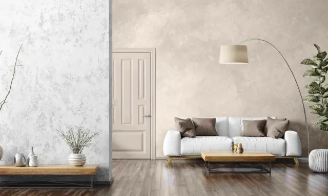 Un salon moderne avec un mur texturé en enduit décoratif, un canapé blanc, une table basse en bois et une plante verte.