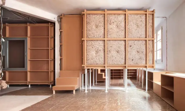 Progetto di ristrutturare casa con 10.000 euro: struttura in legno grezzo, pannelli isolanti e arredi modulari in cartone.