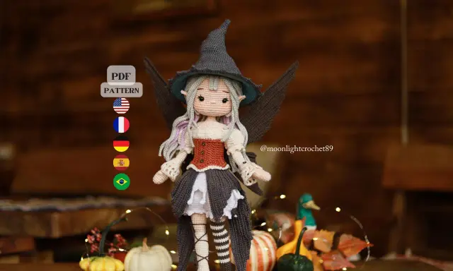 Adorable bruja amigurumi con sombrero puntiagudo y alas. ¡Descarga el patrón gratis en PDF para crear tu propia bruja!