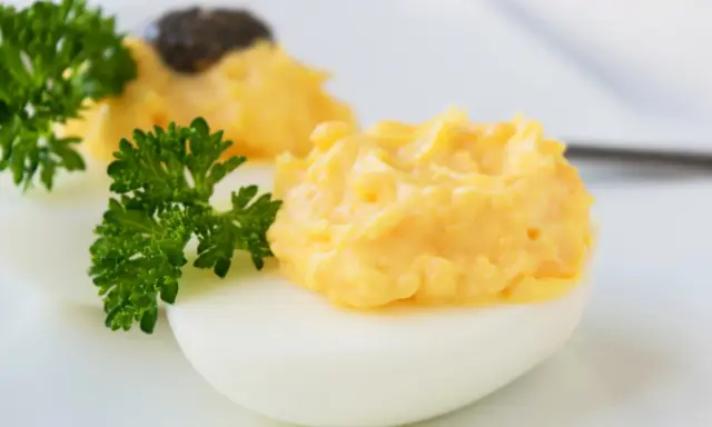 Zwei appetitliche russische Eier traditionell, gefüllt mit einer cremigen Eigelbmasse und garniert mit Petersilie.