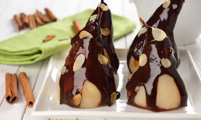 Poires pochées nappées de chocolat noir et d'amandes effilées, une délicieuse recette de poire Belle Hélène.