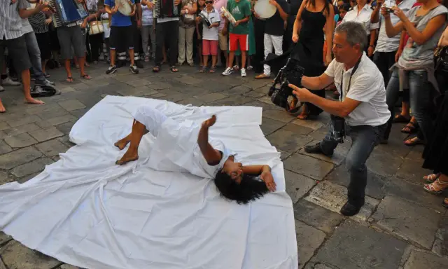 Danza contemporanea durante la festa patronale Galatina. Un performer si muove su un telo bianco, ripreso da un operatore.