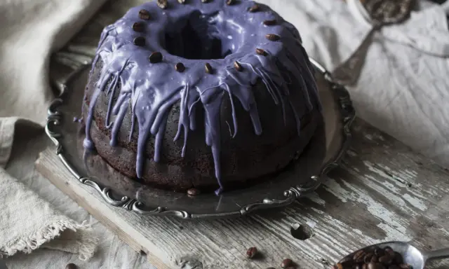 Mörk chokladkaka med lila glasyr och kaffebönor, perfekt för ett chokladkaka recept.