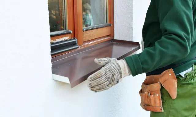 Instalación de un vierteaguas metálico en una ventana. El vierteaguas protege la pared de la lluvia.