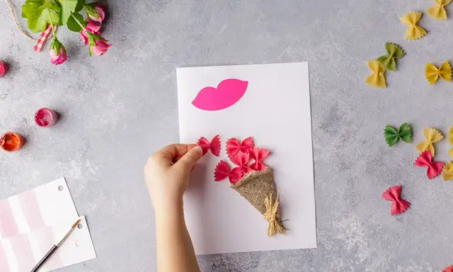 Manos creando flores manualidades con pasta de moño rosa, un ramo y labios de papel.