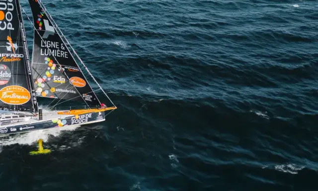 Voilier "Coup de Pouce" naviguant sur une mer agitée, avec le nom "Manuel Cousin" visible sur la voile.