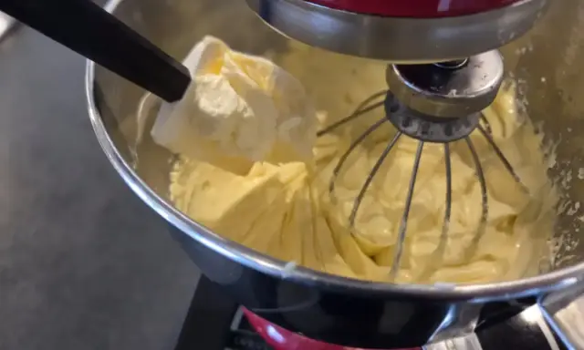 Préparation d'une crème onctueuse pour savoir que faire avec de la crème mousseline. Une spatule ajoute une touche finale à la préparation.