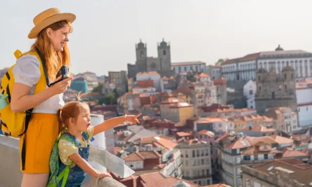 Una madre y su hija disfrutan de las vistas de Oporto con niños, señalando la ciudad histórica.