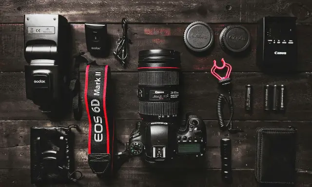 Zestaw fotograficzny: aparat Canon EOS 6D Mark II z obiektywem, lampa błyskowa, baterie i akcesoria. Podstawa aparatu fotograficznego gotowa do pracy.