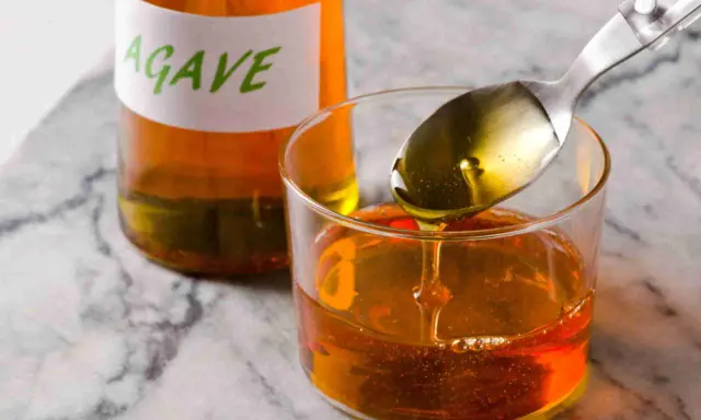 Sirope de agave en un vaso, con una cuchara vertiendo más. Ideal para endulzar recetas durante el embarazo.
