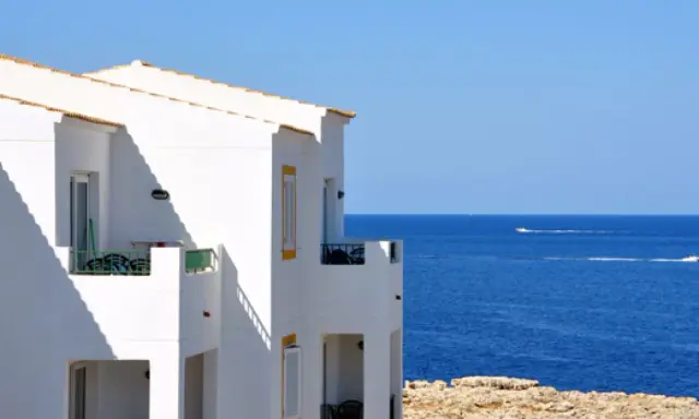 Maison blanche avec balcons face à la mer bleue. Idéal pour un dédommagement location saisonnière.