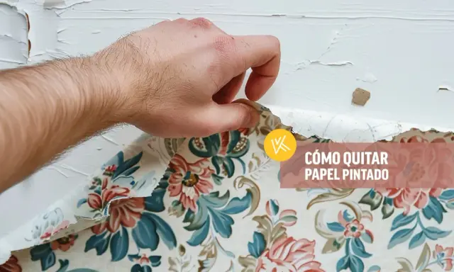 Mano retirando papel pintado floral de una pared blanca.