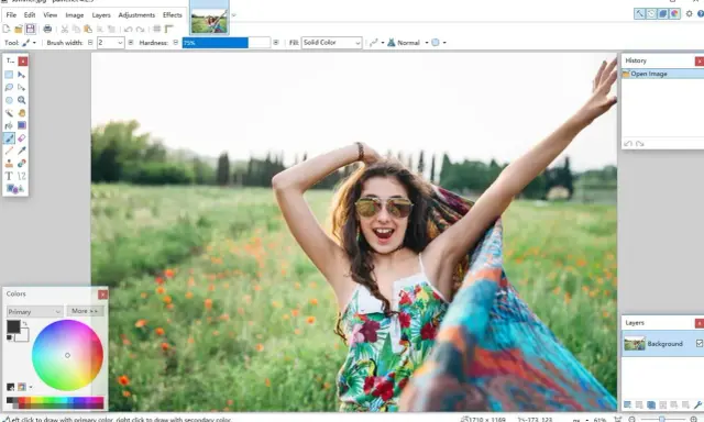 Una chica sonriente con gafas de sol y un pañuelo colorido en un campo de flores, editada en el **foto software** Paint.net.