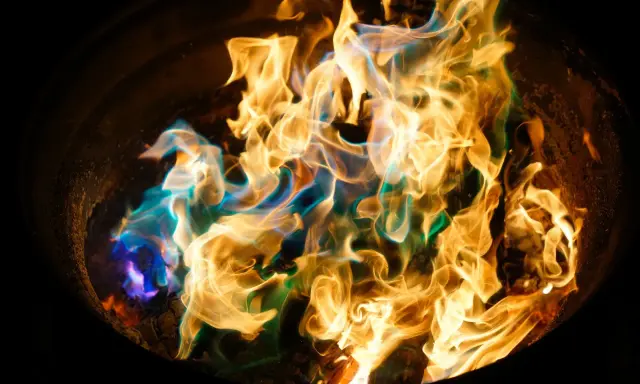 Fiamme danzanti in un braciere, con sfumature blu e verdi che si mescolano all'oro. Un'arte nel fotografare il fuoco.
