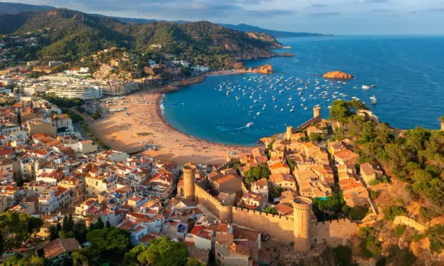 Widok na średniowieczne miasteczko z zamkiem i zatokę pełną łodzi. To idealne miejsce na odkrywanie atrakcji Costa Brava.