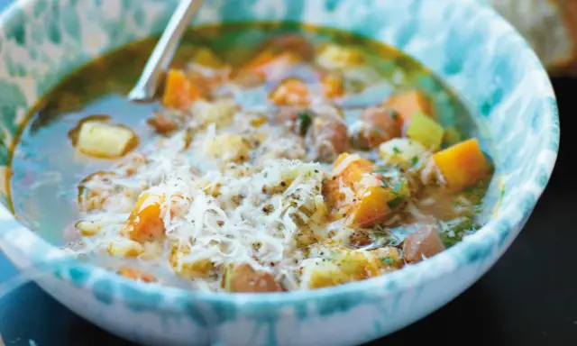 En närbild av en skål med mustig rotfruktssoppa, toppad med riven ost. Ett perfekt soppa recept för kalla dagar.