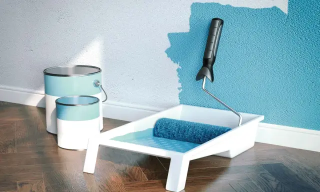 Latas de pintura plástica acrílica y rodillo listo para dar vida a una pared azul.