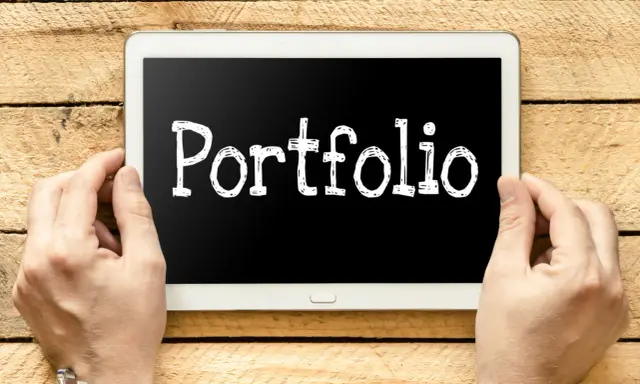 Ręce trzymają tablet z napisem "Portfolio". Idealny do prezentacji prac podczas studiów.