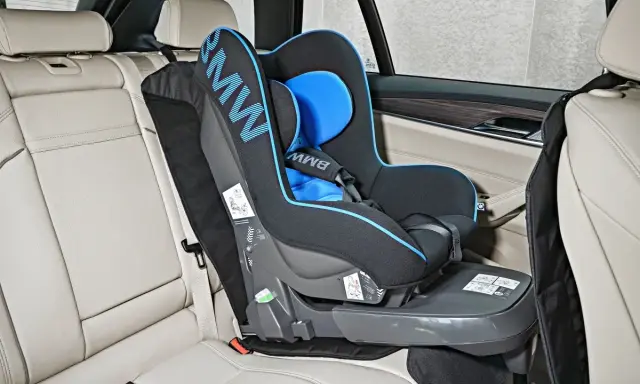 Fotelik dziecięcy BMW z systemem pasy isofix zamontowany na jasnej, skórzanej kanapie samochodowej.