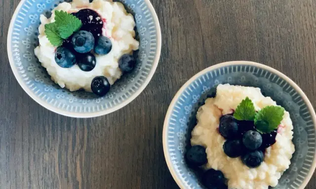 Två skålar med krämig risgrynsgröt, toppad med blåbär och mynta. Ett enkelt och gott risifrutti recept.