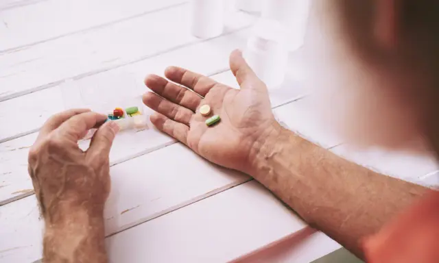 Mano che prende pillole da un portapillole. Speranza di guarigione con pembrolizumab.