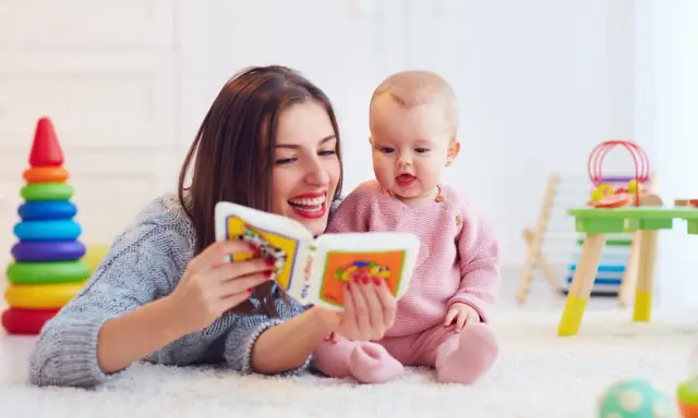 Mama czyta książeczkę kolorową, a jej 2 letnie dziecko z zaciekawieniem słucha.