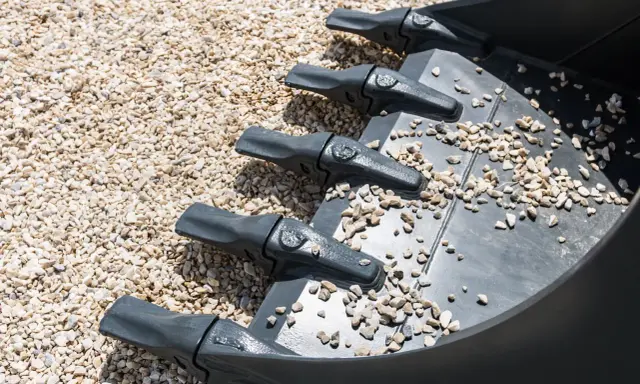 Dientes de excavadora sobre grava, una forma de como compactar tierra sin rodillo.