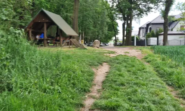 Ścieżka wśród zieleni prowadzi do altany, idealnej na odpoczynek po przejażdżce po trasach rowerowych Ruda Śląska.