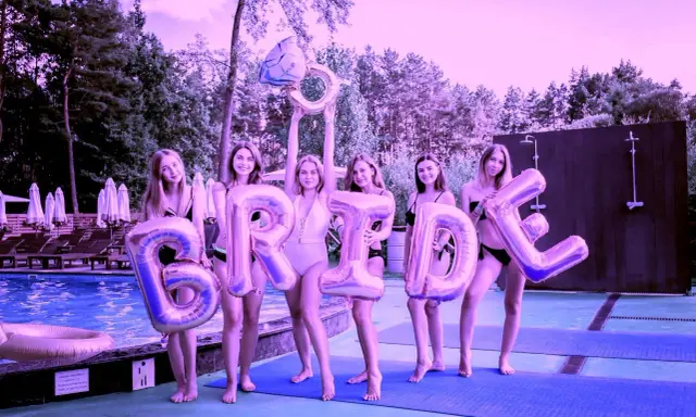 Dziewczyny świętują wieczór panieński przy basenie, trzymając balony z napisem "BRIDE" i gigantyczny pierścionek.