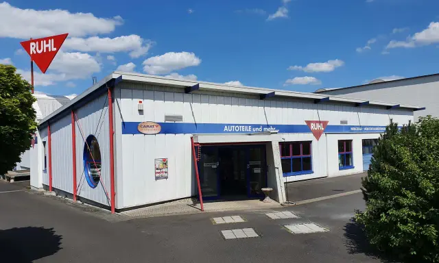 Gebäude von Ruhl Autoteile mit rotem Schild und blauem Schriftzug "AUTOTEILE und mehr...".