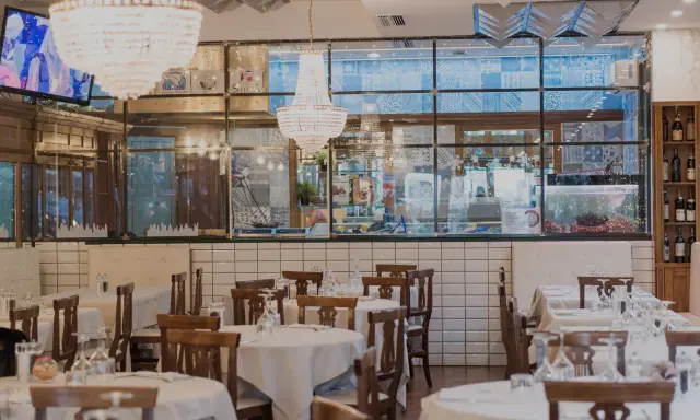 Interno del ristorante Amerigo a Rimini, con tavoli apparecchiati e lampadari eleganti.