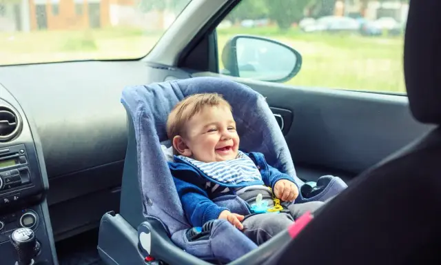 Bebé feliz en silla de coche, asiento delantero, listo para la aventura.