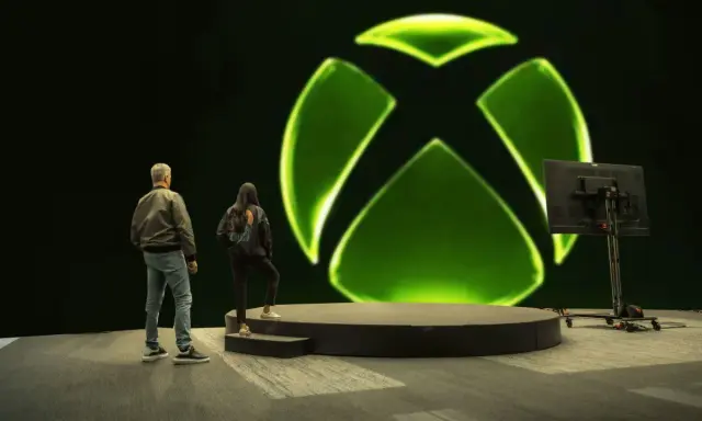 Osoby stoją przed wielkim zielonym logo Xbox. Czy to zapowiedź nowej gry, czy może Xsolla co to za platforma?