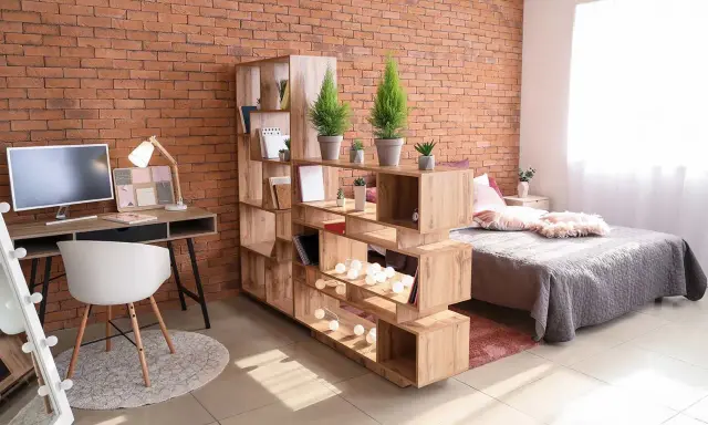 Étagère modulable pour séparer une pièce en deux sans travaux. Elle crée un espace bureau et un coin nuit cosy.