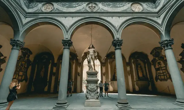 Cour intérieure de Florence avec une statue antique au centre. Une femme prend une photo de la statue florence.