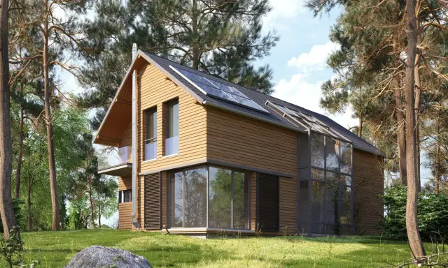 Maison en bois moderne avec panneaux solaires, conçue par un constructeur maison écologique. Entourée de pins, elle s'intègre parfaitement à la nature.